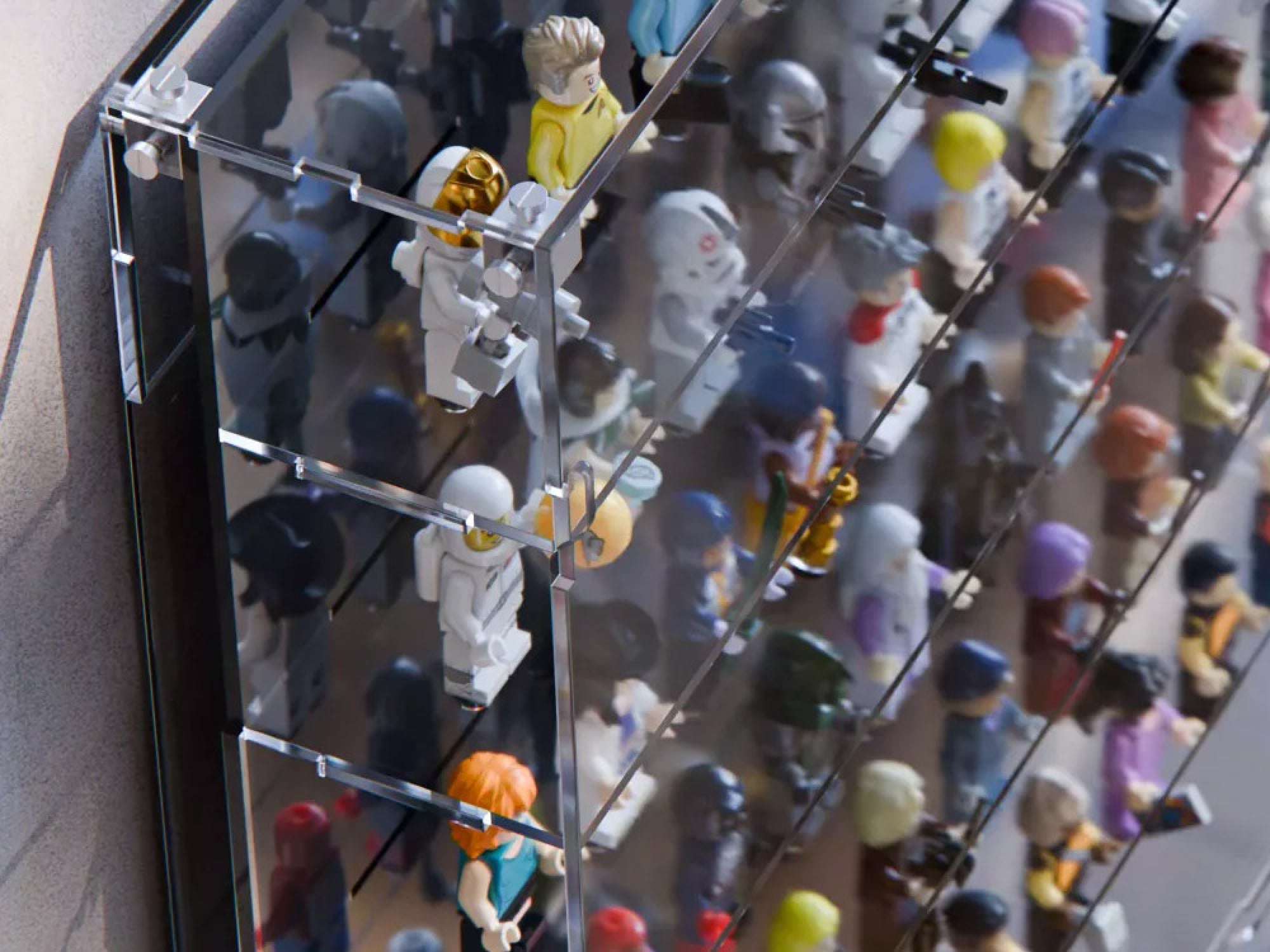 Close-up of LEGO minifigures standing on studs behind a clear acrylic front panel
